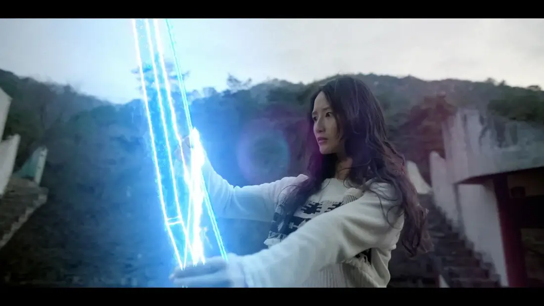 Jiyeon Han as Sua holding a glowing blue supernatural bow